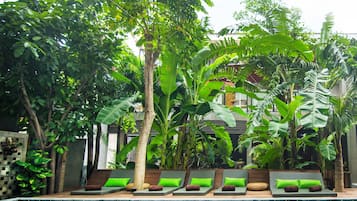 Una piscina al aire libre, sombrillas, sillones reclinables de piscina