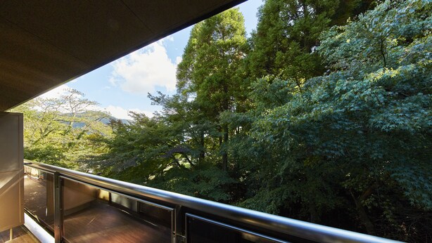 A balcony with a metal railing overlooking a forested area. - Hotel Hakone Terrace (Hakone)