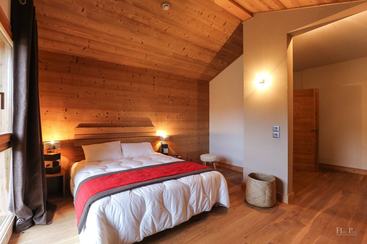 Une chambre à coucher aux murs lambrissés, avec un lit, des lampes de chevet et une table de chevet.