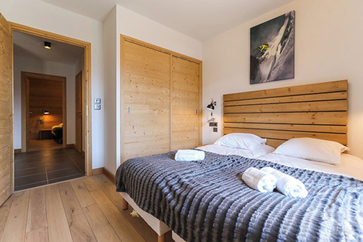 Un dormitorio con una cama de madera, un armario y un cuadro en la pared.