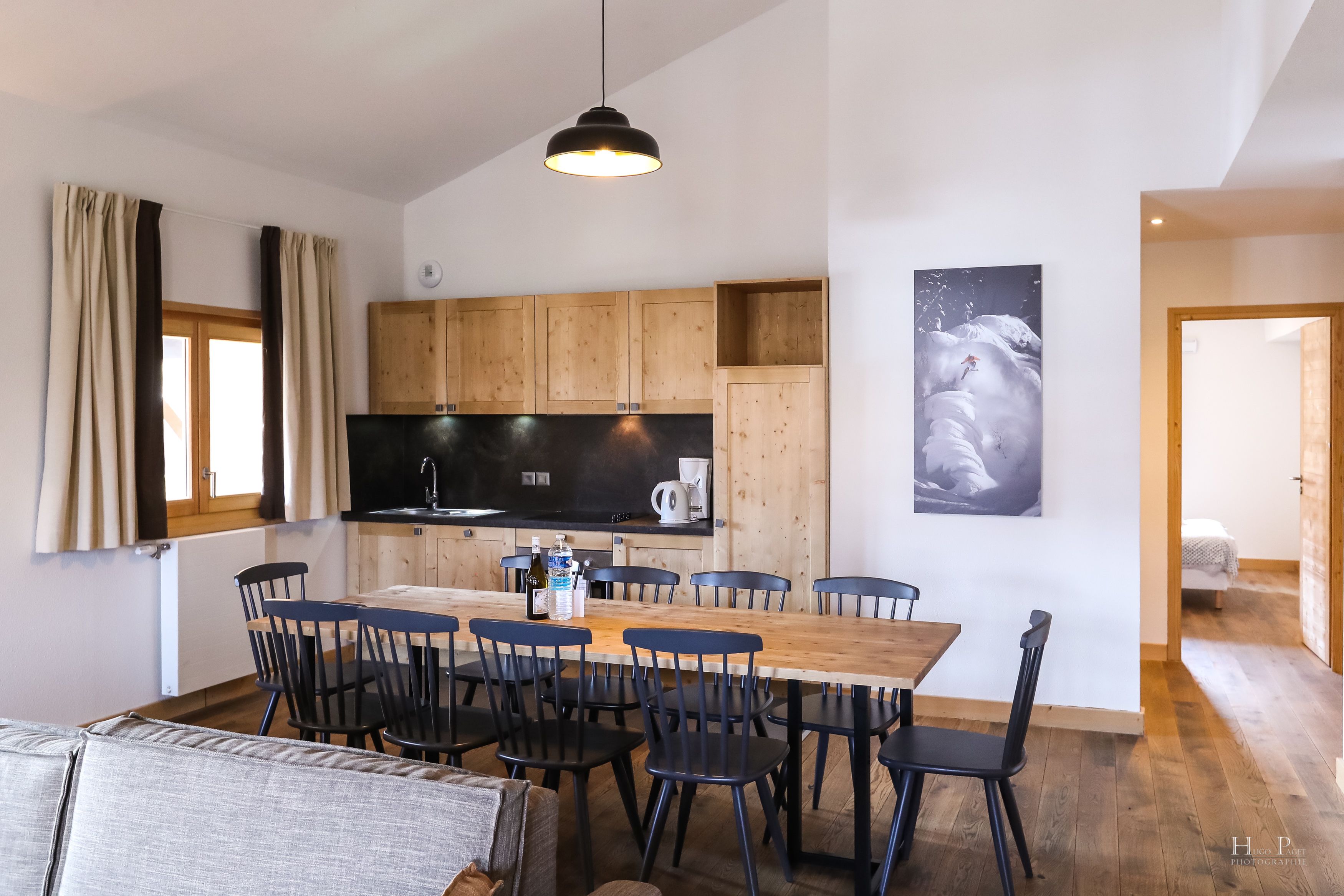 A modern kitchen with wooden cabinets, a large dining table, and black chairs.