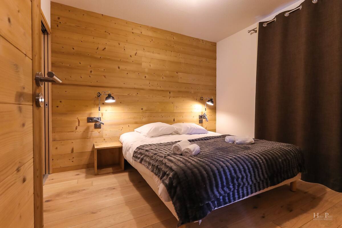 Une pièce aux murs lambrissés, avec un lit, des lampes de chevet et une table de chevet.