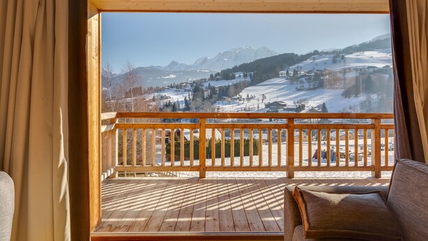 Un terrazza in legno con vista su un paesaggio montano innevato.