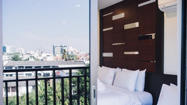 A hotel room with a balcony, a bed with white linens, and a view of the cityscape. - Luxury Residence (Chiang Mai)