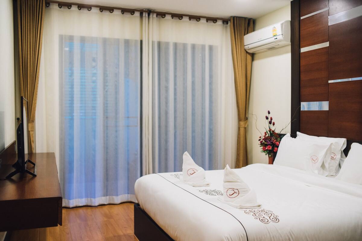 A hotel room with a large bed, a desk, and a window with curtains.