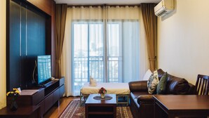 A modern living room with a flat-screen TV, a sofa, a coffee table, and a bed with a white pillow. - Luxury Residence (Chiang Mai)