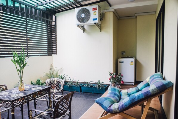 A room with a dining table, chairs, a sofa, potted plants, a wall-mounted air conditioner, and a refrigerator. - Luxury Residence (Chiang Mai)