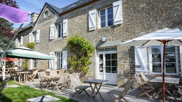 A stone building with outdoor seating and umbrellas.