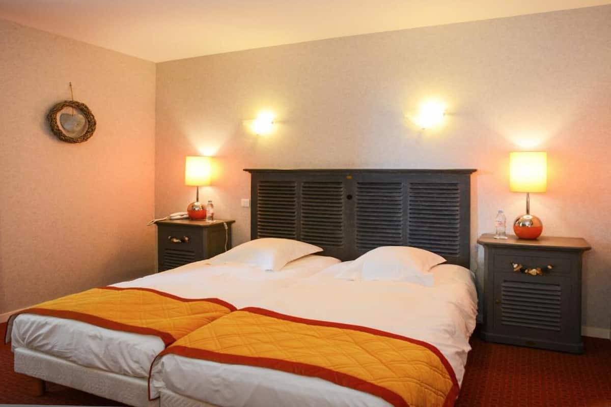 Een hotelkamer met een bed, twee nachtkastjes, een hoofdeinde en wandlampen.