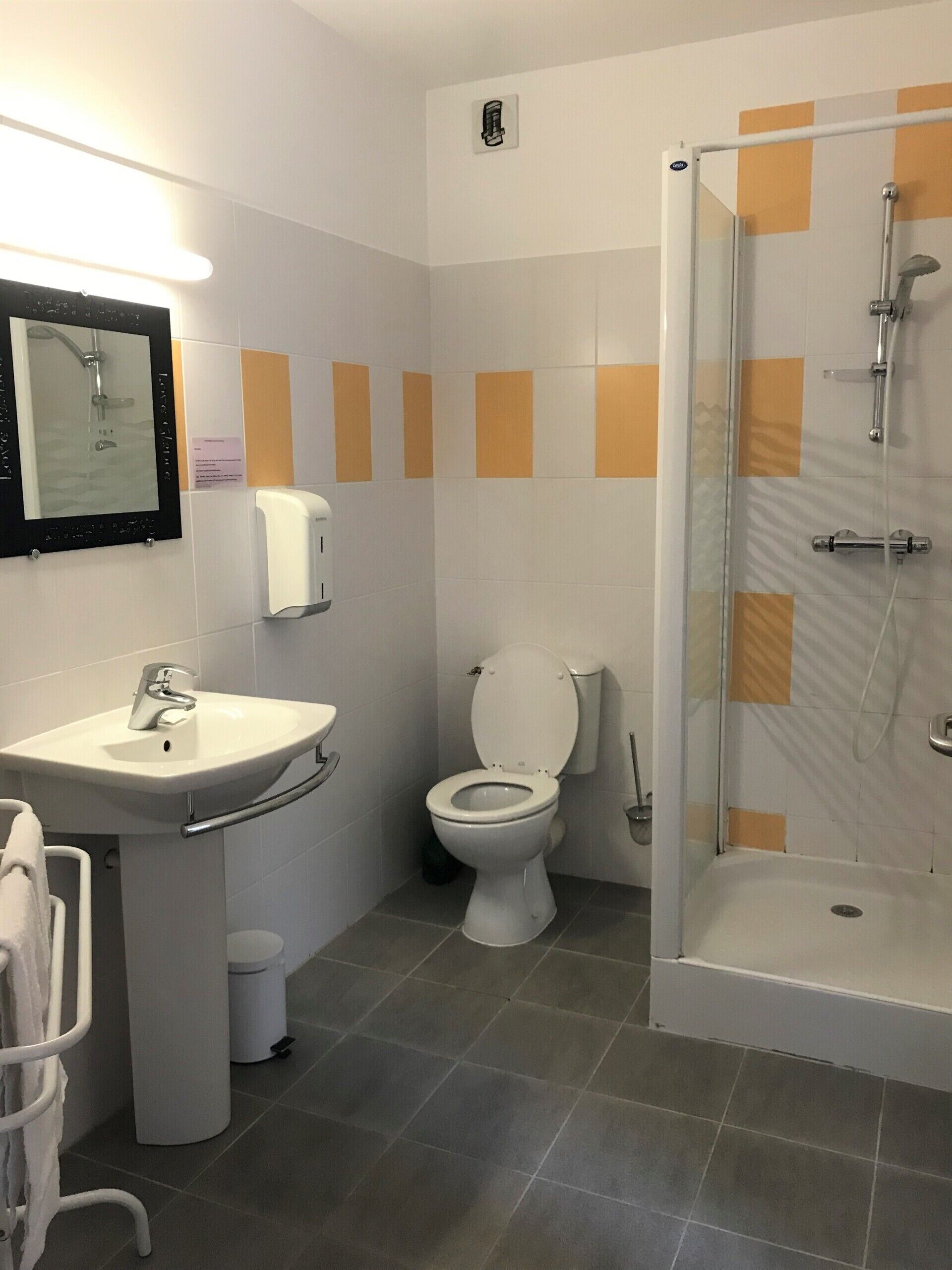 Un baño con lavamanos, inodoro y ducha con mampara de vidrio.