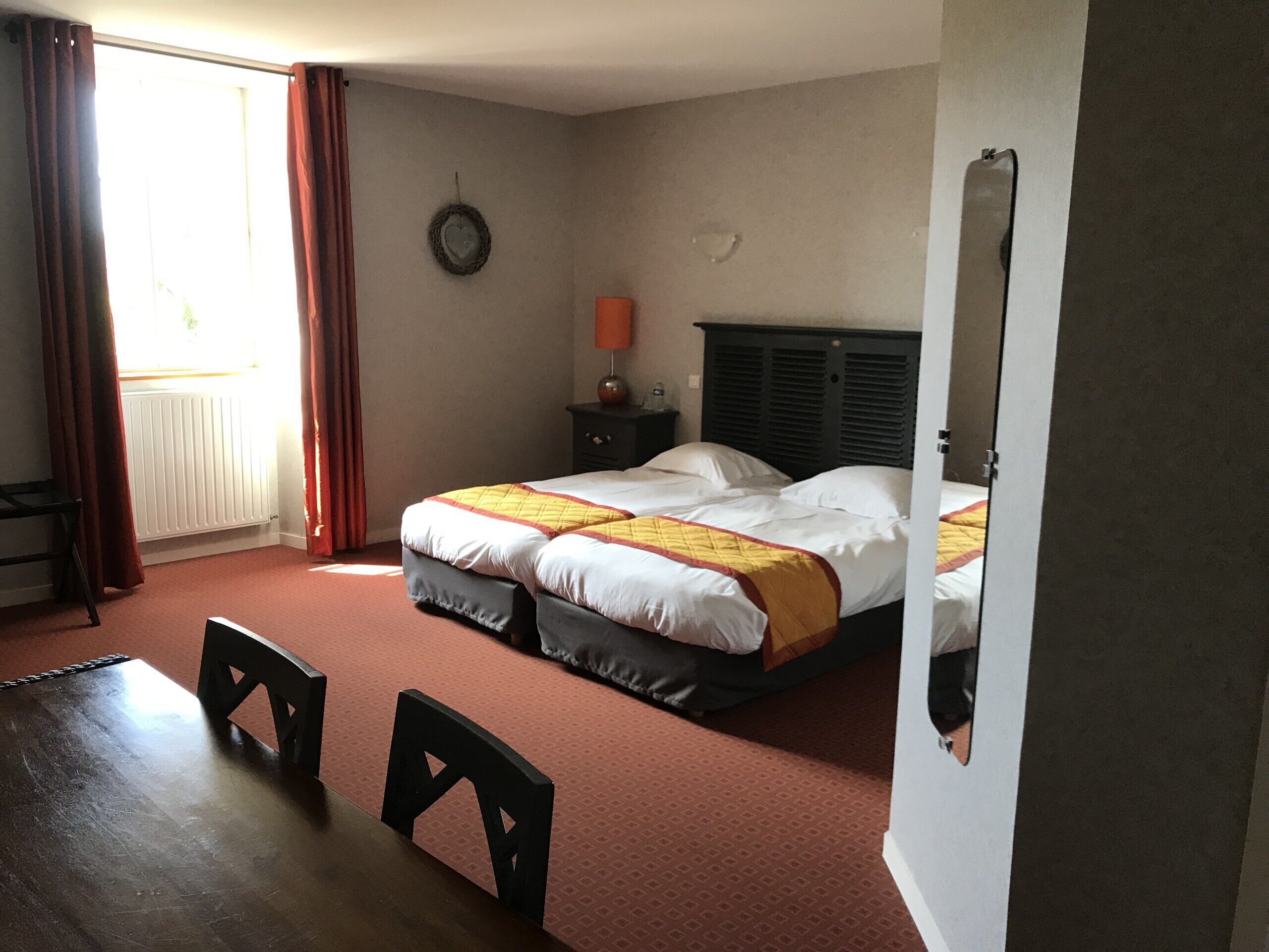 Une chambre d’hôtel avec deux lits, une table en bois et une chaise.