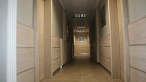 A hallway with wooden paneling and a tiled floor, leading to a door at the end. - Hotel Kale Palace (Gökçeada)