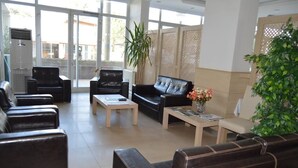 A spacious lobby with leather sofas, a coffee table, and a potted plant. - Hotel Kale Palace (Gökçeada)