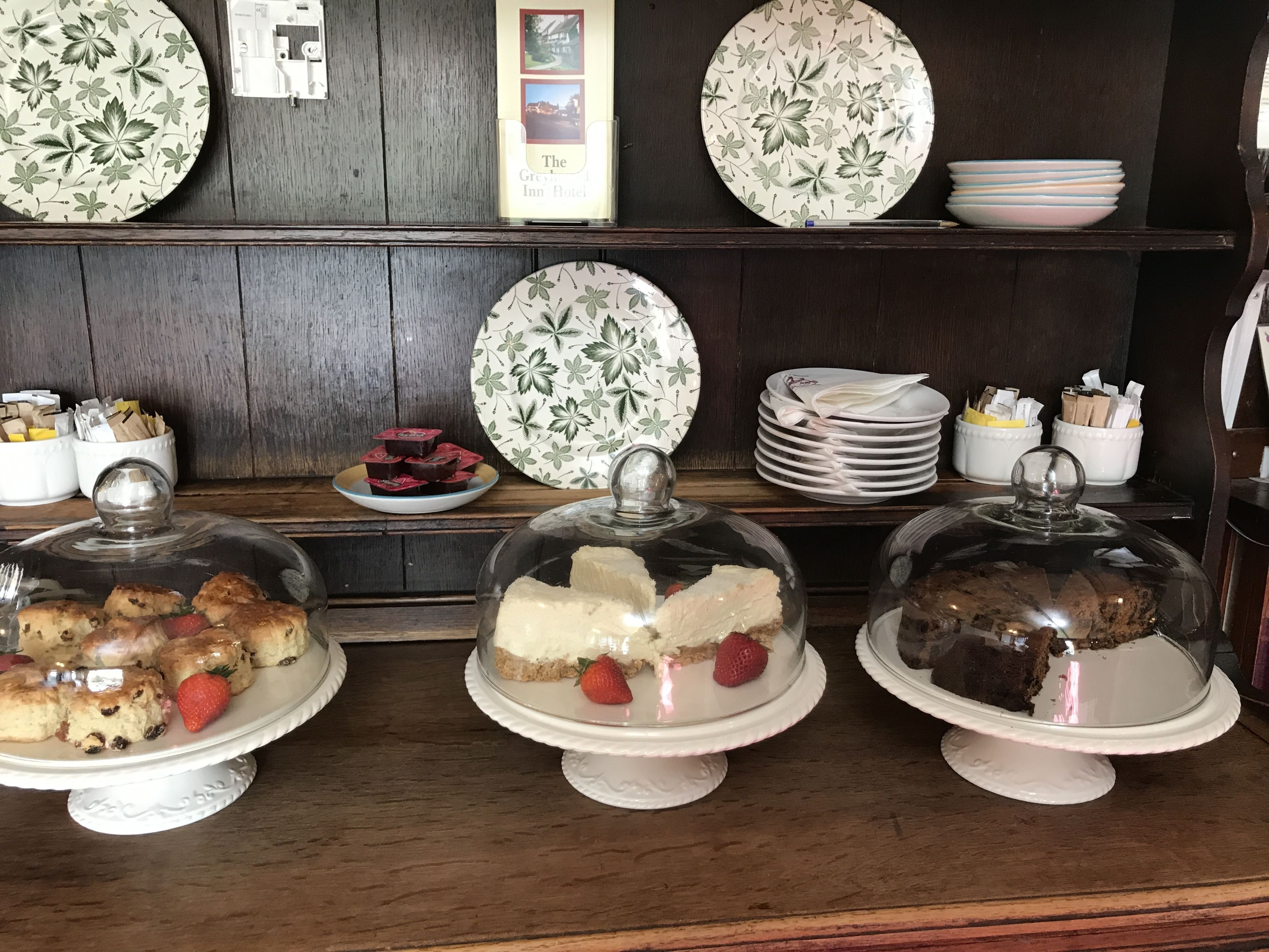 Een presentatie van desserts op een toonbank met borden en schalen met bloemenmotief.