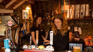 A bar with a wooden counter, beer taps, and a refrigerator stocked with bottles. - The Greyhound Inn & Hotel (Usk)