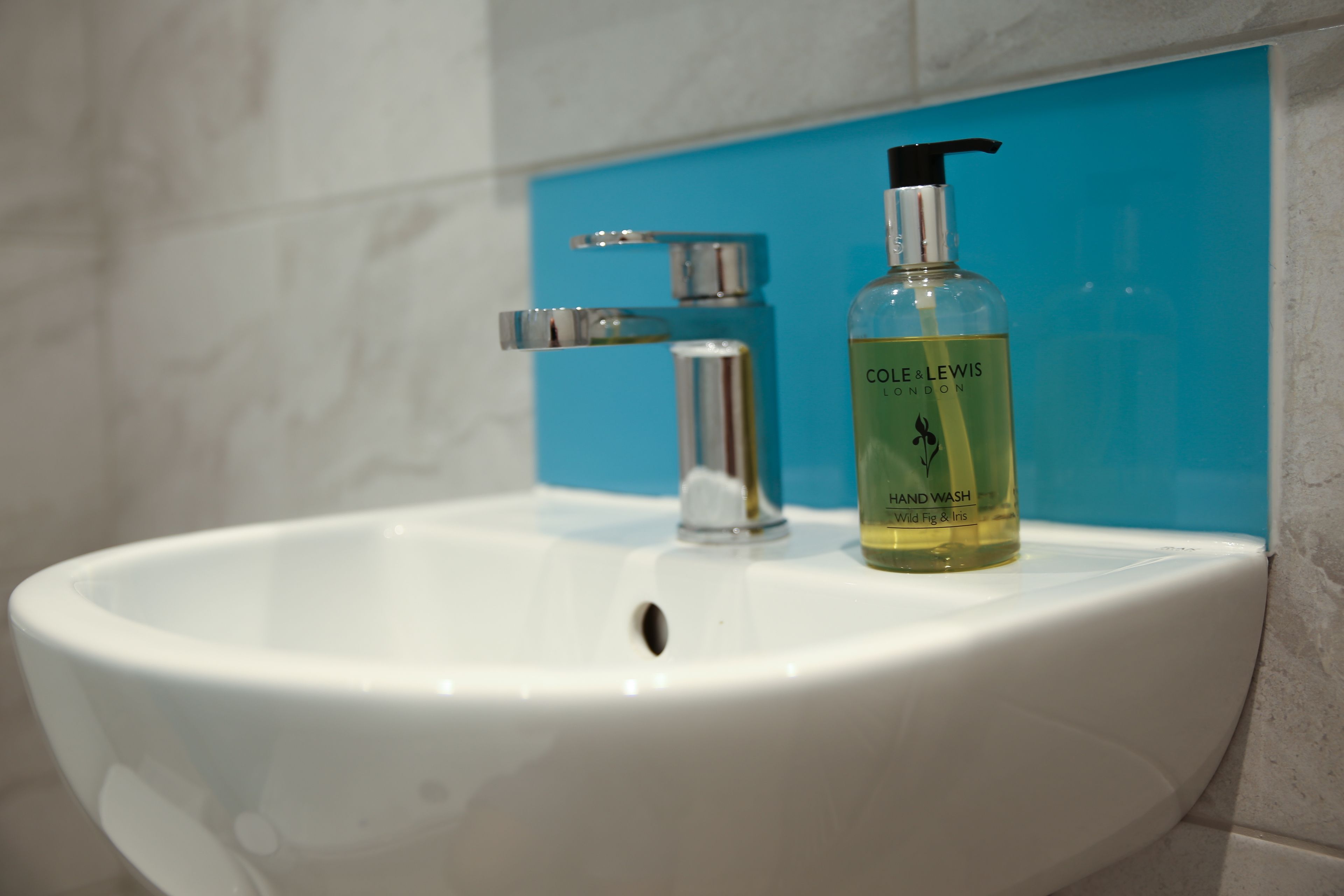 Un lavabo de salle de bain avec un flacon de savon liquide pour les mains.