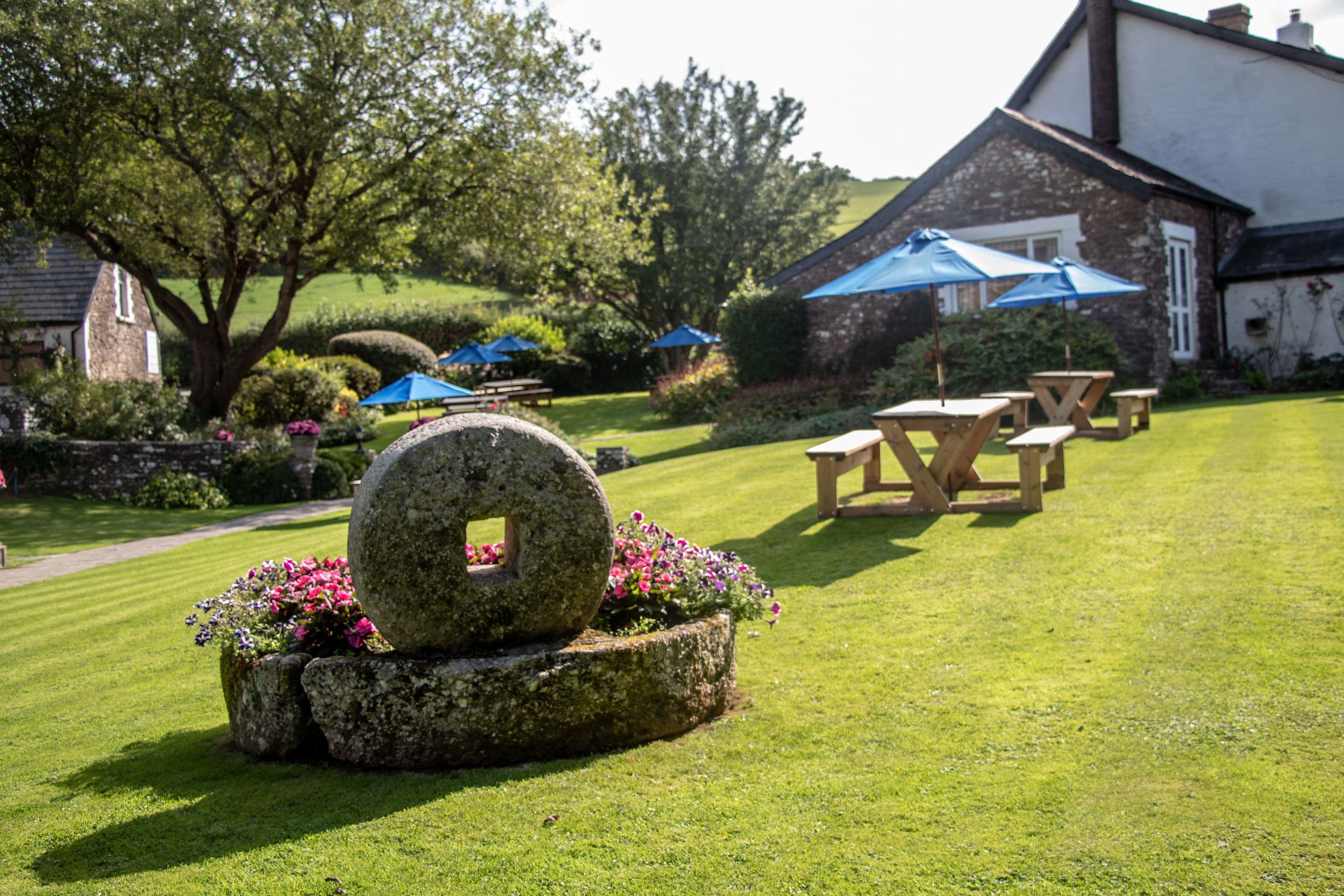 A well-maintained garden with stone planters, picnic tables, and umbrellas.