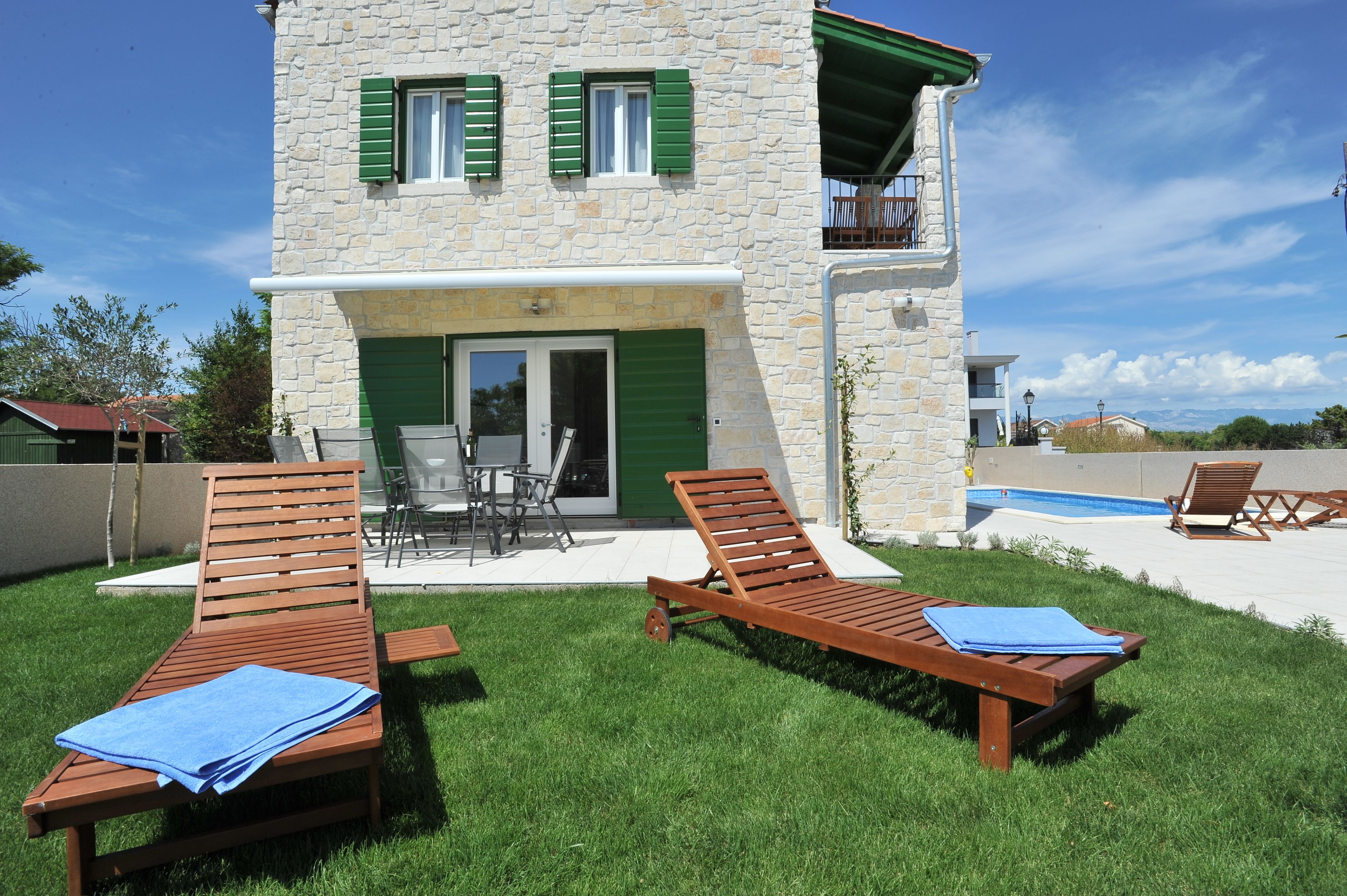 Un bâtiment en pierre de deux étages, dot é d’un patio, d’un espace extérieur aménagé avec des sièges et d’une piscine.