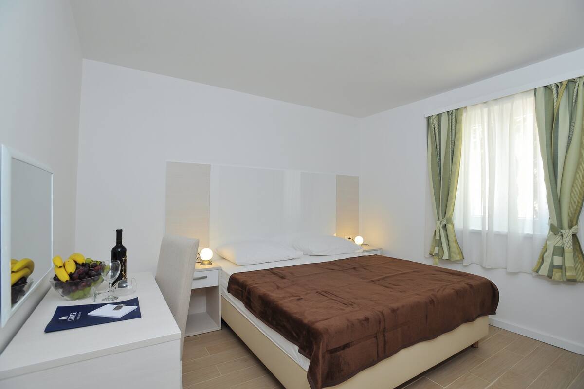 Ein Hotelzimmer mit Bett, Nachttisch und kleinem Schreibtisch mit Spiegel.