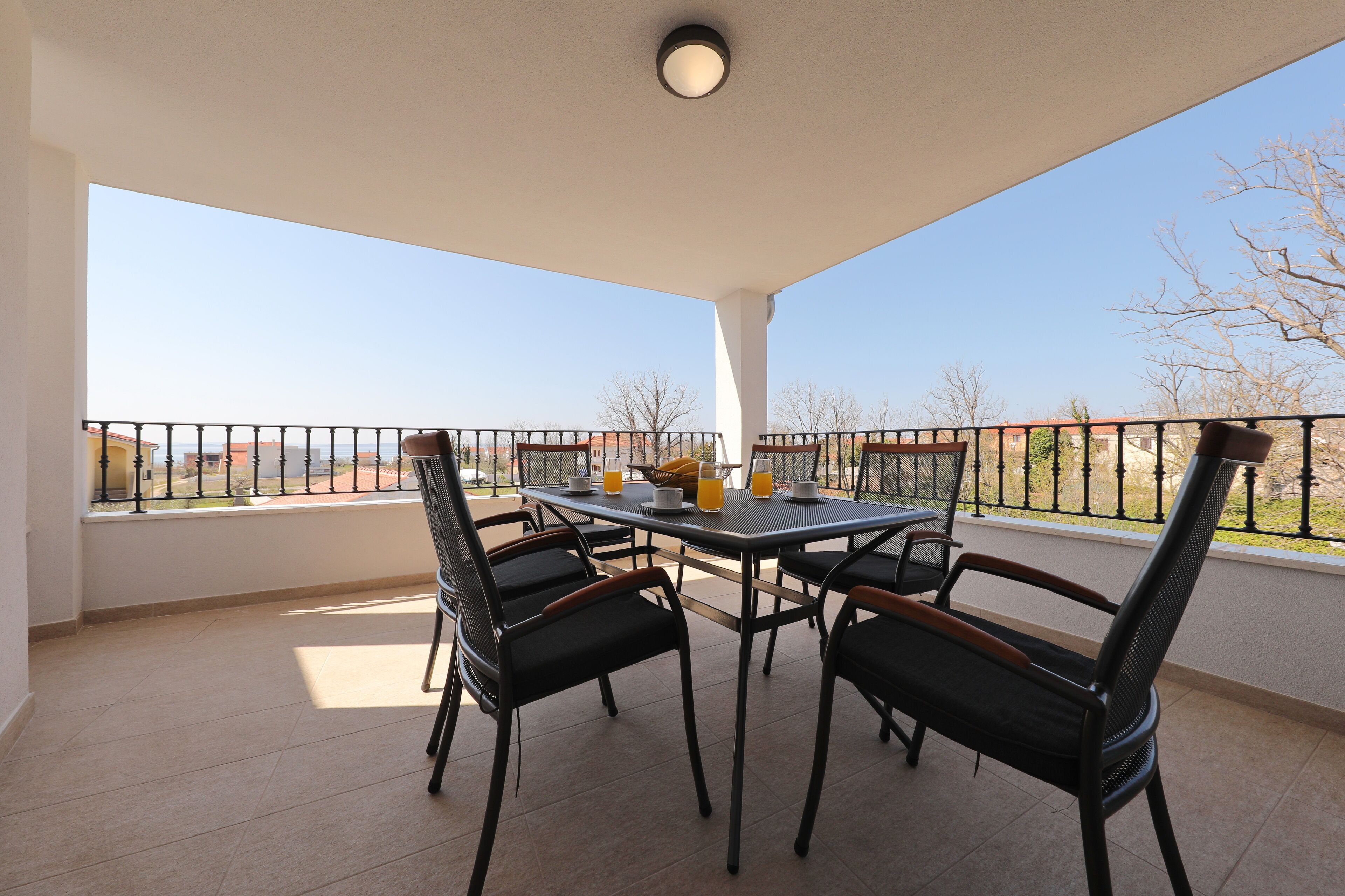 Een balkon met een tafel en stoelen, en uitzicht op de stad, met een balustrade.
