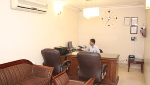 A conference room with a desk, chairs, an air conditioner, a clock, and framed certificates on the wall. - Hotel J's Inn (New Delhi)
