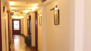 A long, well-lit hallway with polished floors and wooden trim. - Hotel J's Inn (New Delhi)