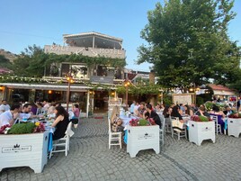 Un espacio de comedor al aire libre con mesas y sillas, un cartel para el Restaurante Kale y un edificio con un cartel para el Kale Motel.