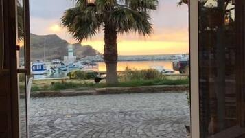 Una terraza de madera con vista a un puerto deportivo y un atardecer.