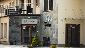 Un edificio con fachada de piedra, un balcón con mesas y sillas, y un letrero que dice 'Recieveja'.