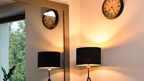 Una sala de estar moderna con un sofá verde, dos mesitas de madera y un espejo grande.