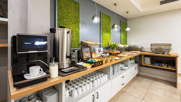 Un bufé de desayuno con una máquina de café, estación de té y diversas opciones de comida.