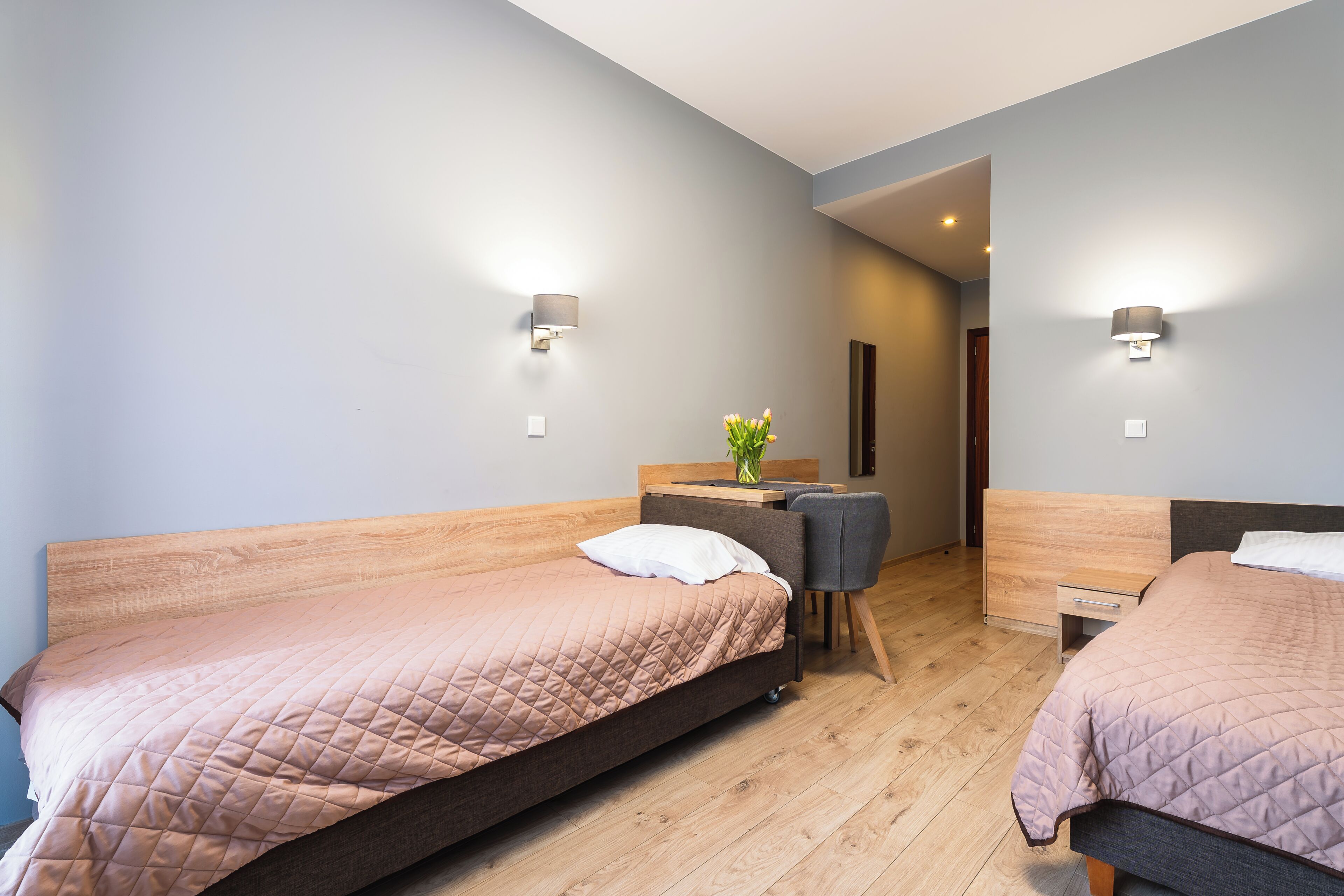 A bedroom with two single beds, a desk, and a chair.