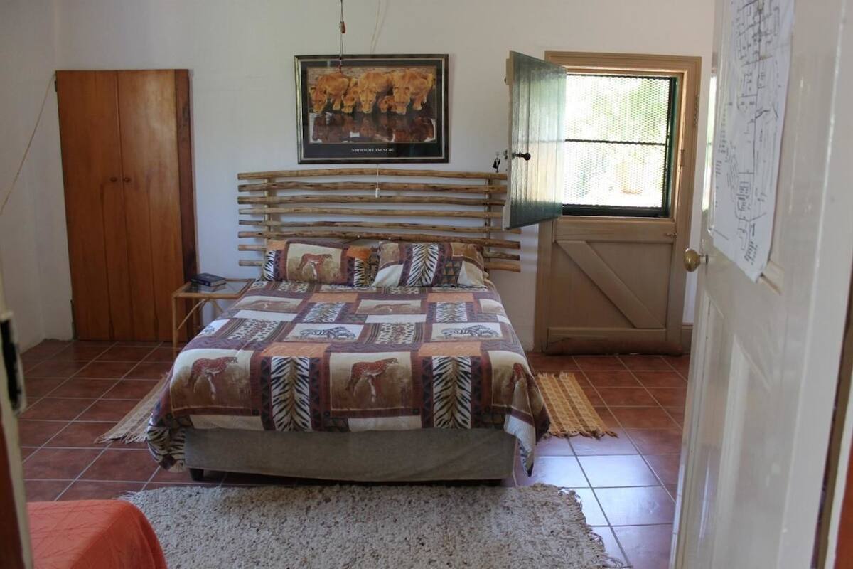 A bedroom with a wooden bed, a framed picture on the wall, and a door with a window.