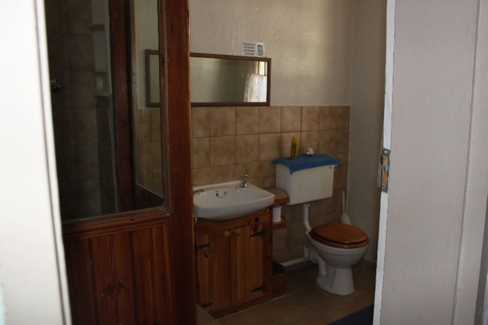 A small bathroom with a wooden vanity, a sink, a toilet, and a mirror.