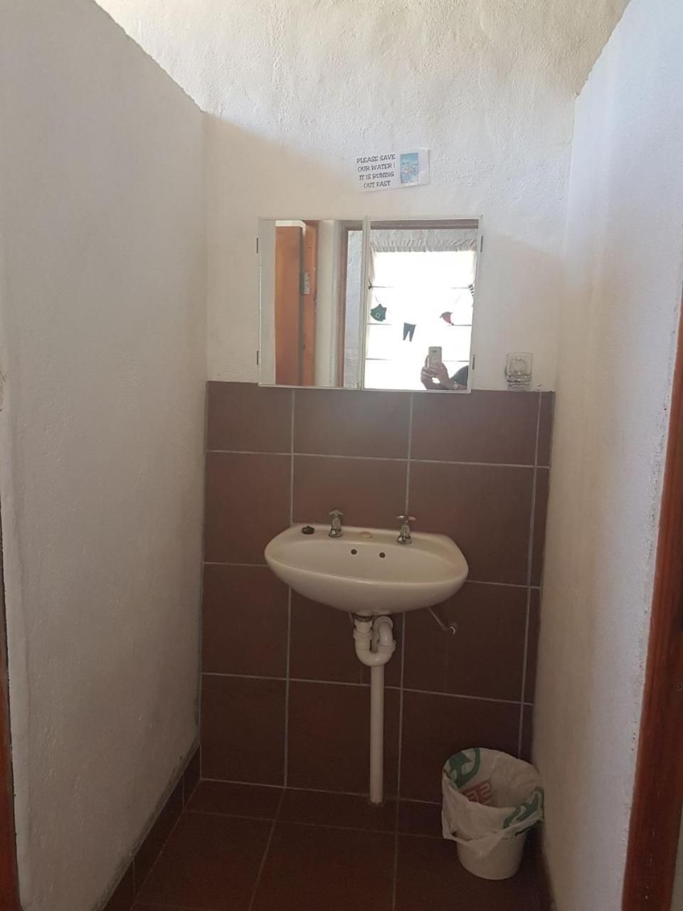A small bathroom with a sink, a mirror, and a sign above the mirror.