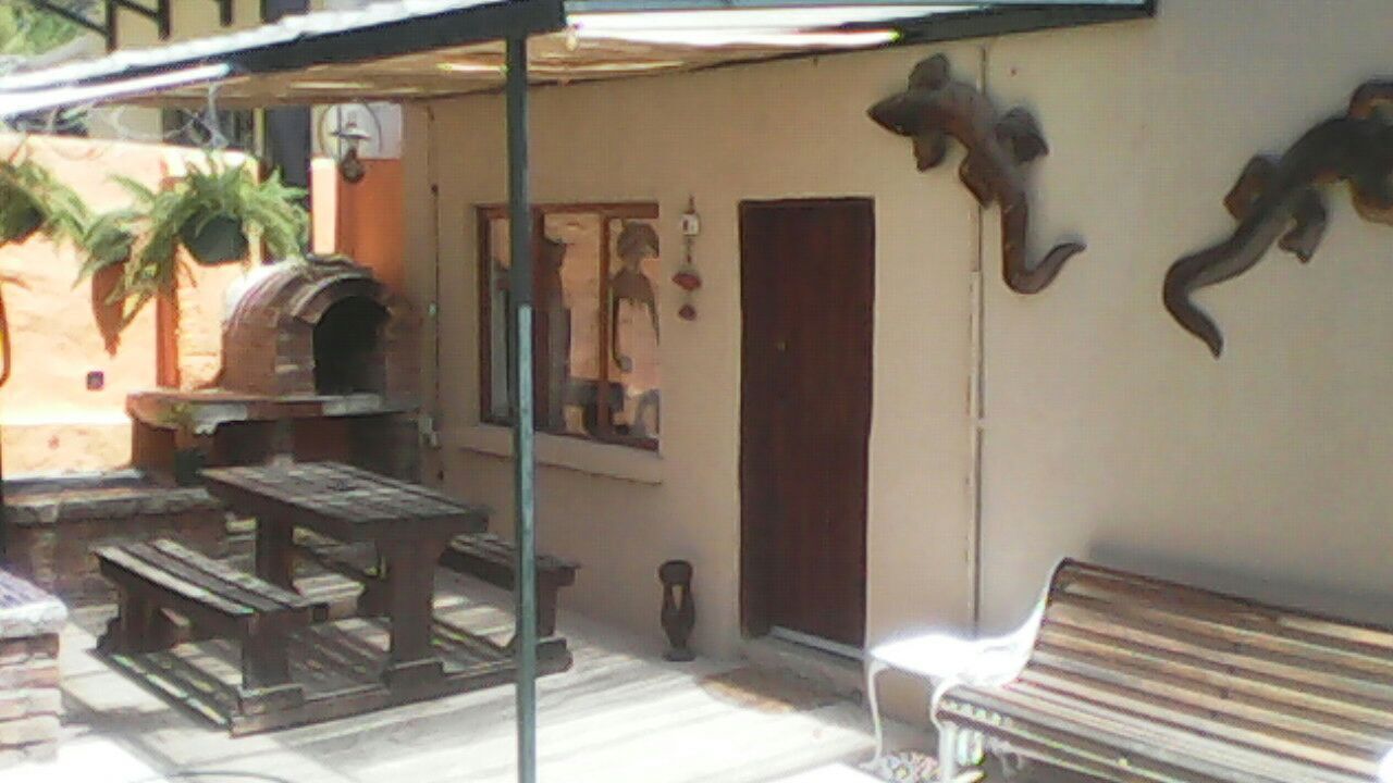 Un patio al aire libre con un horno de ladrillo, mesas de madera y un banco.