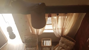 Une pièce comprenant deux fauteuils rembourrés, une petite table et une fenêtre avec des rideaux.