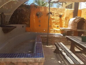 An outdoor patio area with a tiled hot tub, a stone bench, and a brick oven. - Trackers Inn (Graaff-Reinet)