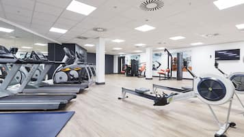 Un gimnasio con cintas de correr, una máquina de remo y equipo de ejercicio.