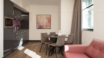 A modern dining area with a table and chairs, a red sofa, and a kitchen with dark cabinets.