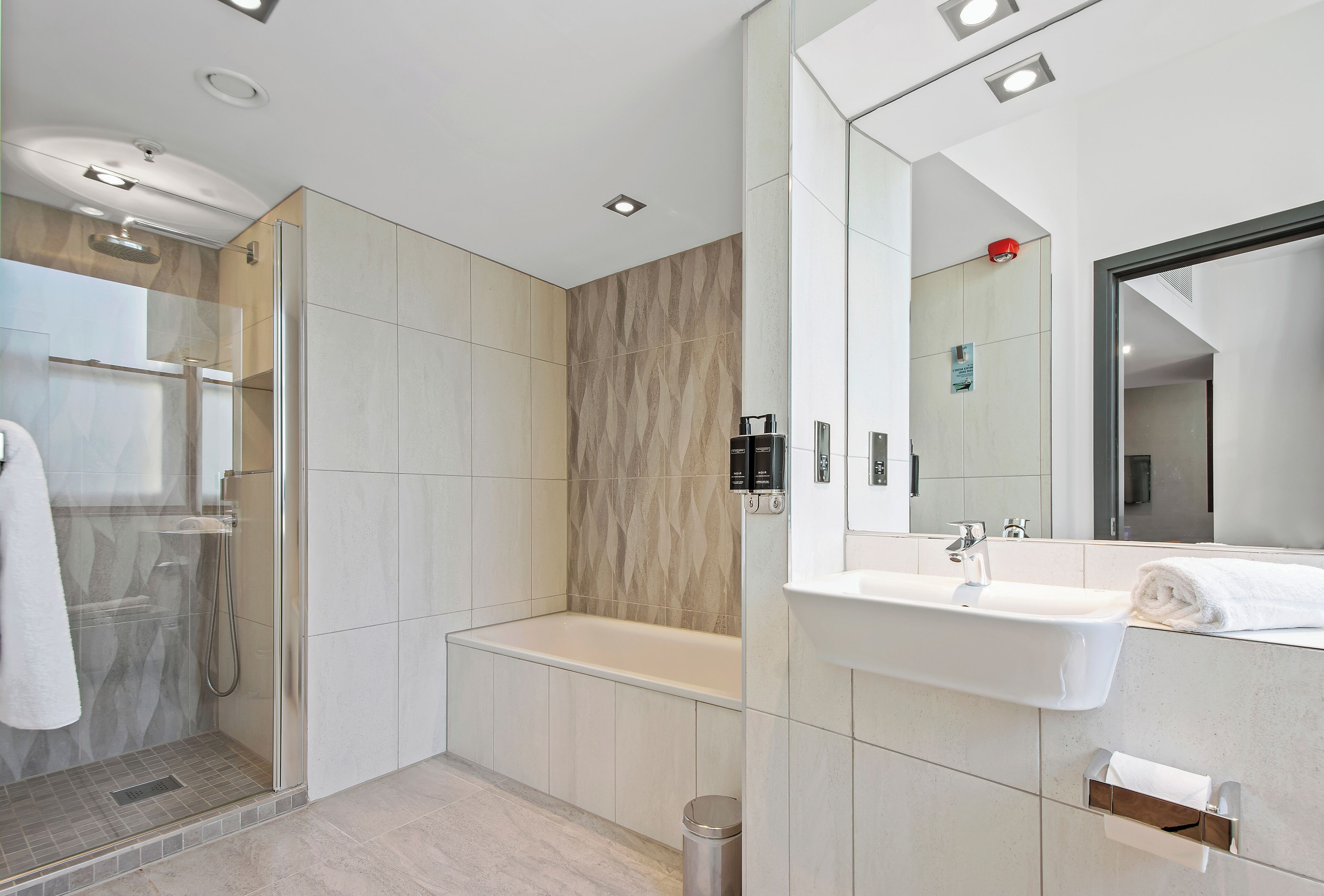 A modern bathroom with a glass-enclosed shower, a freestanding bathtub, and a wall-mounted sink.