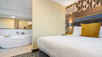 A hotel room with a large bed, a separate bathroom with a bathtub, and a modern wall design.