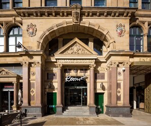 A historic building with a prominent Produce Exchange sign, a Corn Exchange sign, and a Groceries sign. - Roomzzz Manchester Victoria (Manchester)