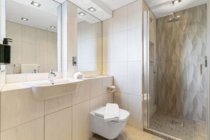 A modern bathroom with a sink, mirror, toilet, and shower. - Roomzzz Manchester Victoria (Manchester)