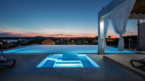 Una piscina con vistas a la puesta de sol y montañas al fondo.