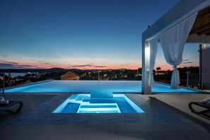 Una piscina con vistas a la puesta de sol y montañas al fondo.