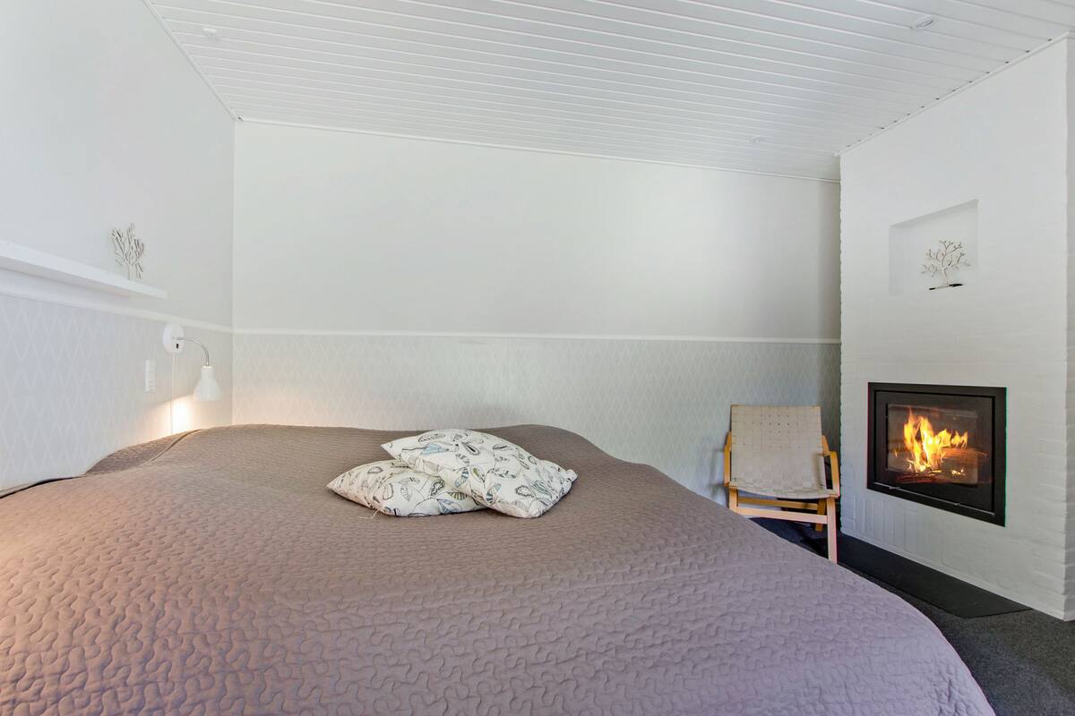 Une chambre à coucher comprenant un lit, une chaise, une cheminée et une étagère fixée au mur.