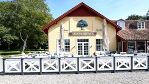 Un bâtiment sur lequel on peut lire l’inscription « SKOVPAVILLONEN » et qui présente un motif d’arbre au-dessus de l’entrée.