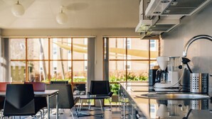 A modern kitchen with a coffee machine, a sink, and a window overlooking a garden. - Stoeberiet (Svendborg)