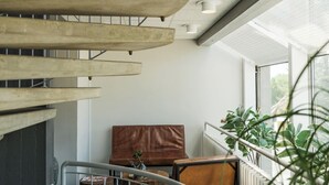 A modern interior with a spiral staircase, leather seating, and a view of greenery outside. - Stoeberiet (Svendborg)